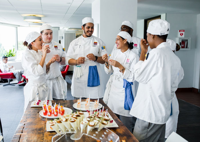 Culinary students smiling tasting food.