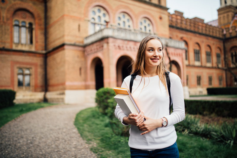 Student looking off screen in front of school building